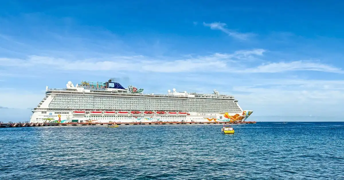 The Norwegian Getaway cruise ship docked at a sunny port with clear blue skies and small boats in the foreground. This image accompanies a review of the Norwegian Getaway and an overview of The Haven experience.