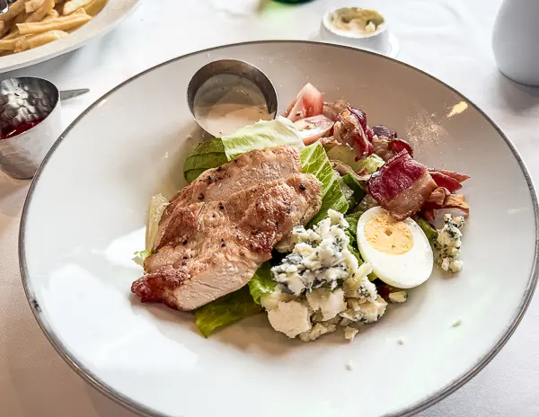 A fresh Cobb salad with grilled chicken, bacon, hard-boiled egg, blue cheese, and creamy dressing.