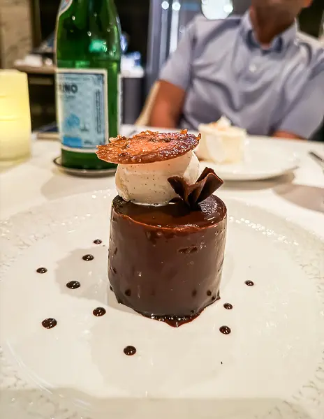 A rich and indulgent chocolate dessert with layers of ganache and mousse, garnished with a caramel crisp.