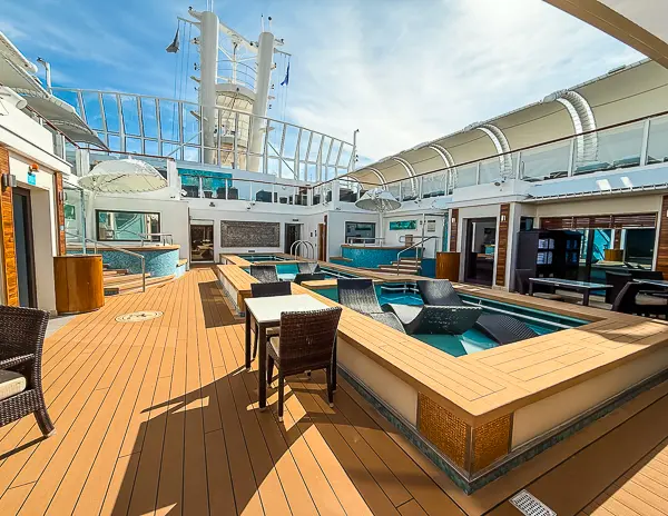 The Haven pool courtyard on the Norwegian Getaway, featuring lounge chairs, private hot tubs, and a serene atmosphere under a glass canopy.