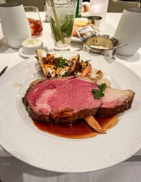 A juicy prime rib served with a side of roasted vegetables and baked potato at the Haven restaurant on Norwegian Getaway.