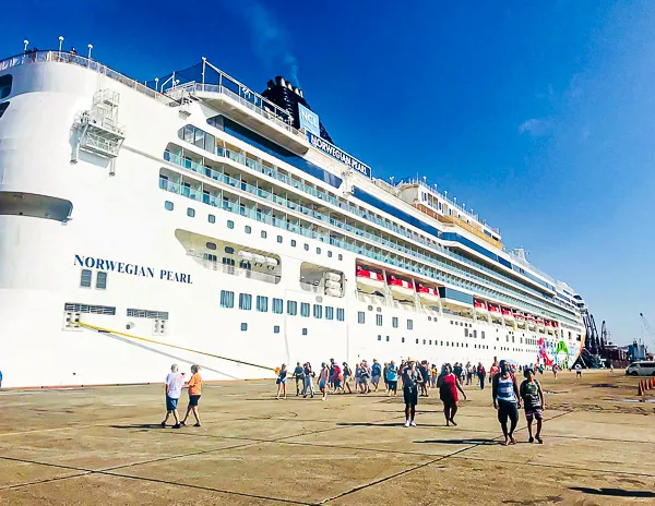 the Norwegian Pearl docked at the Santo Tomas de Castilla cruise port, with passengers disembarking onto the pier.