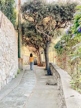 woman walking down a narrow stone road in Capri, Italy