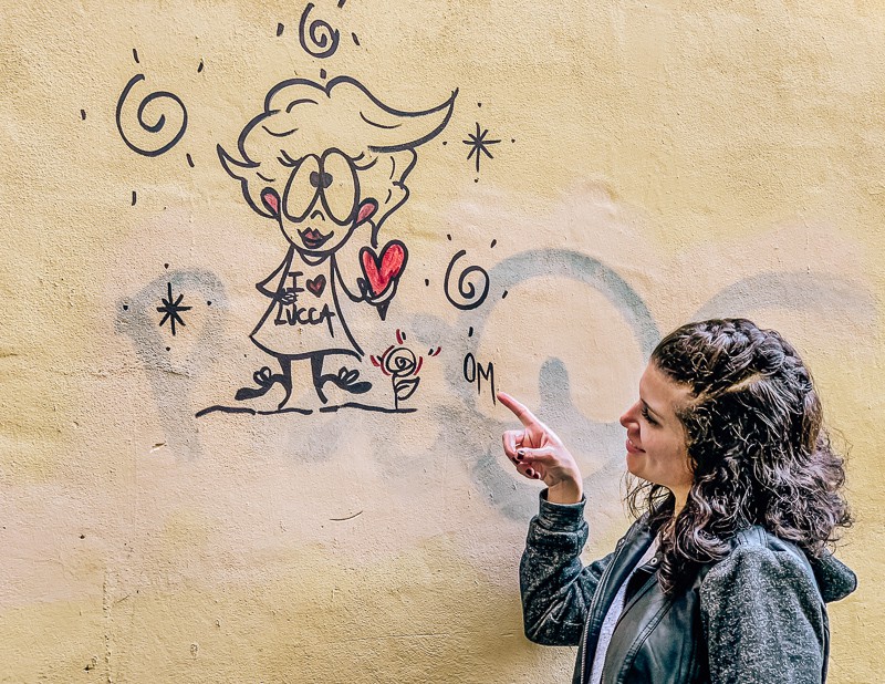 Kathy from Tasty Itinerary pointing at an I Love Lucca Street Art • A Quick Road Trip to Lucca, Italy >> TastyItinerary.com