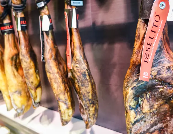 Several legs of Joselito jamón hanging in a Girona market. This dry-cured Spanish ham is a prized delicacy and a highlight of the Girona Food Tour.