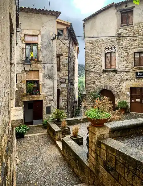 A quiet, stone-paved alleyway in Besalú, Spain, surrounded by historic stone buildings with rustic charm.