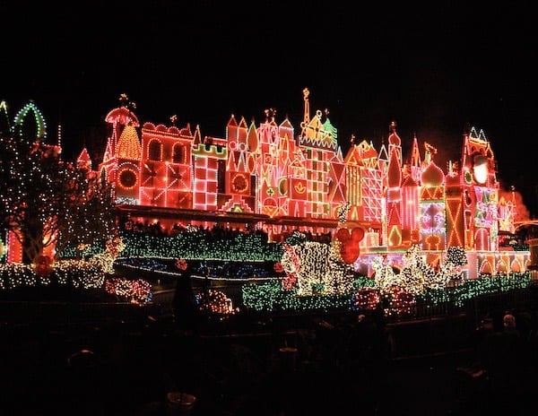 The facade of It's a Small World at Disneyland lit up with colorful holiday lights, creating a magical Christmas display.