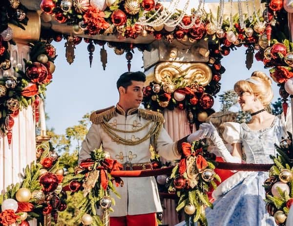 Prince Charming and Cinderella on a festive Christmas parade float adorned with red and gold holiday decorations at Disneyland.