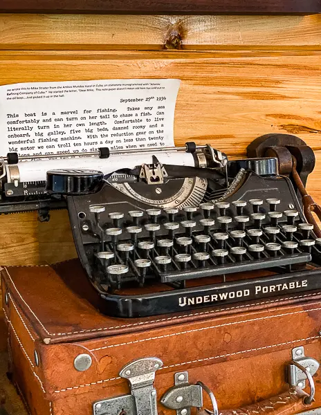 An antique Underwood Portable typewriter displayed on a leather suitcase, featuring a typed letter, located in the Ernest Hemingway House Museum in Key West.