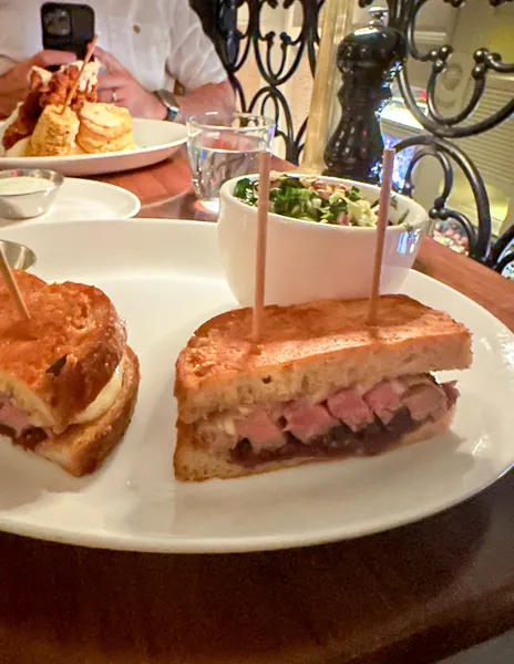 A ribeye melt sandwich cut in half, garnished with parsley on a white plate from nicks pasadena