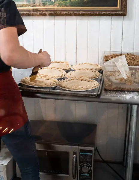 Person brushing the top of apple pies before baking