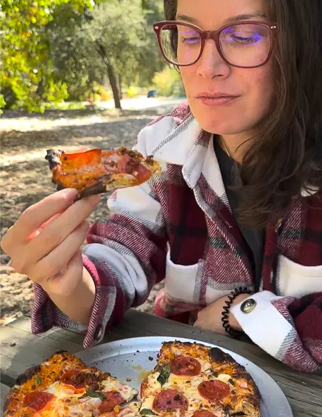 Kathy eating a slice of pepperoni pizza at Wilshire's Apple Shed.