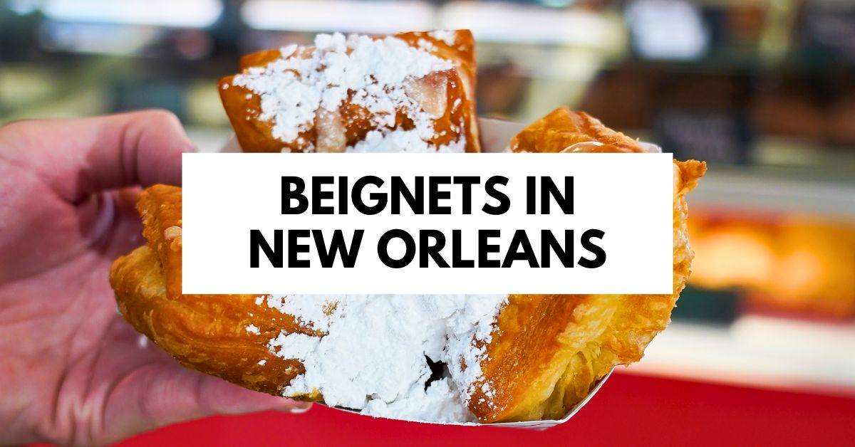 featured blog image of a hand holding a beignet generously dusted with powdered sugar, with the text "Beignets in New Orleans" overlaying the image.