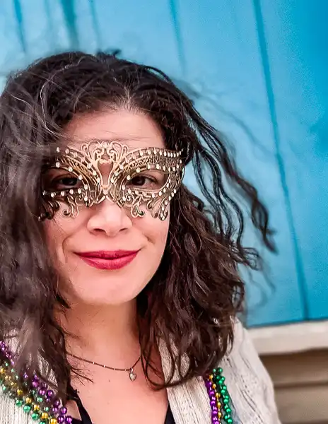 Person (kathy) wearing a gold masquerade mask and Mardi Gras beads, dressed for a Second Line celebration in New Orleans.