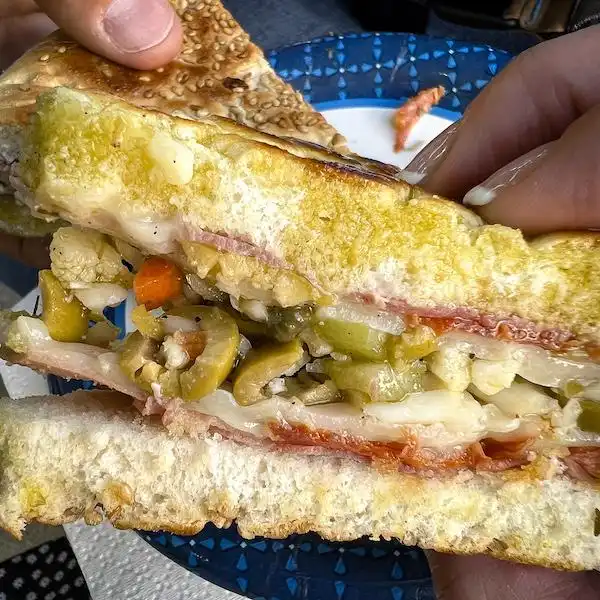 Close-up of a muffuletta sandwich in New Orleans, packed with Italian meats, cheese, and olive salad on sesame bread.