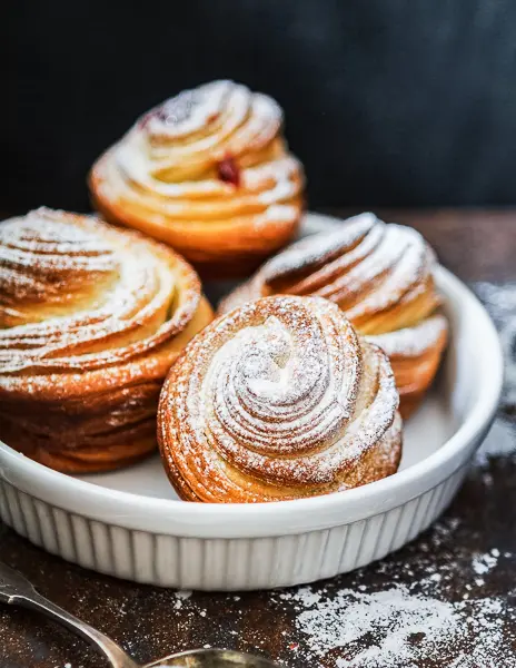 A plate of cruffins dusted with powdered sugar.