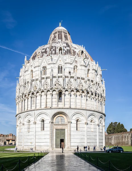 the Battistero di San Giovanni in Pisa, captured in stunning detail against a clear blue sky. The exterior showcases the characteristic marble design and intricate architectural details of this octagonal building, emphasizing its historical and artistic significance in the Piazza dei Miracoli.