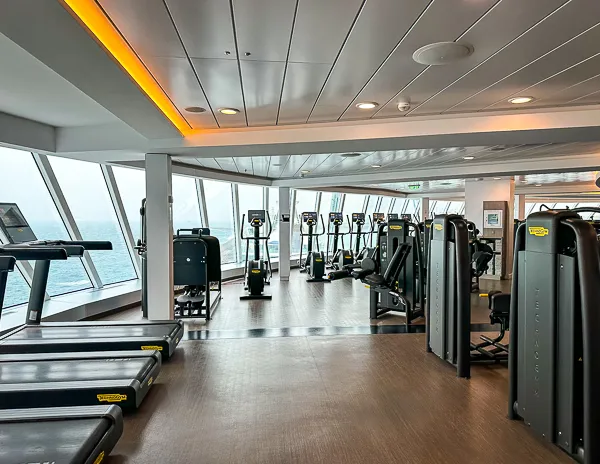 Gym with treadmills and exercise equipment on a Celebrity Beyond cruise ship, overlooking the ocean.