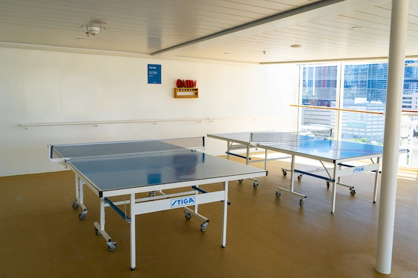 Two ping pong tables in a covered deck area on a cruise ship.