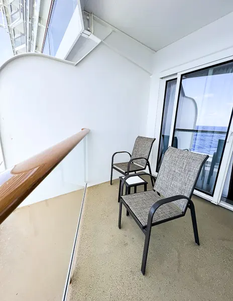 angled cruise ship balcony with two chairs and a table