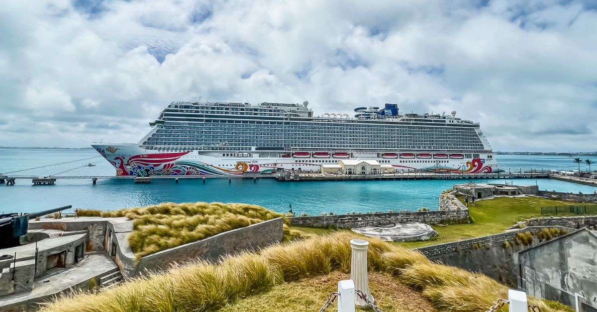 Norwegian Joy cruise ship docked in Bermuda, surrounded by greenery and historic fortifications, featured in this Norwegian Joy review.