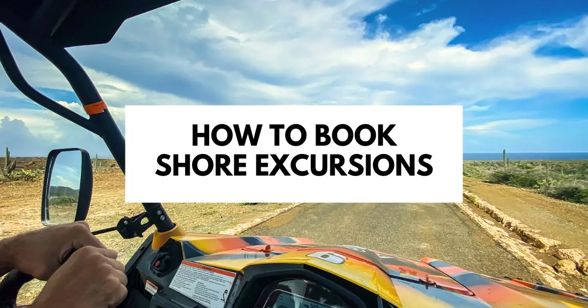 featured blog image with the text "How to Book Shore Excursions" overlaid on a scenic background that features a view from inside an off-road vehicle on a shore excursion, driving along a coastal road under a partly cloudy sky. 