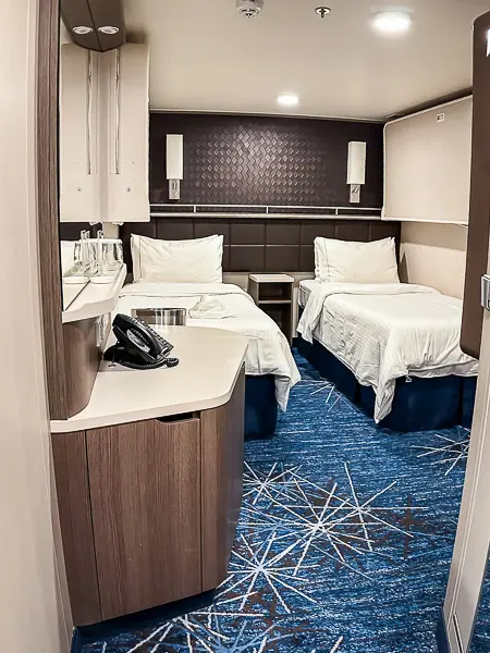 Interior of a small cruise cabin with two twin beds and a modern design.