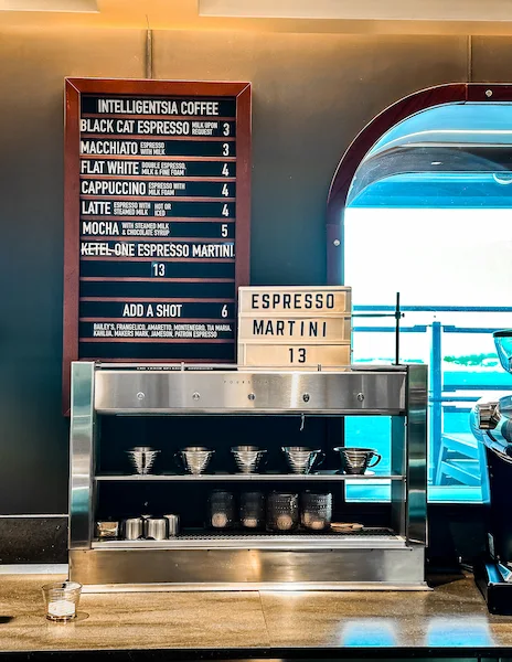 Menu board showing specialty coffee and drink prices on a cruise ship.