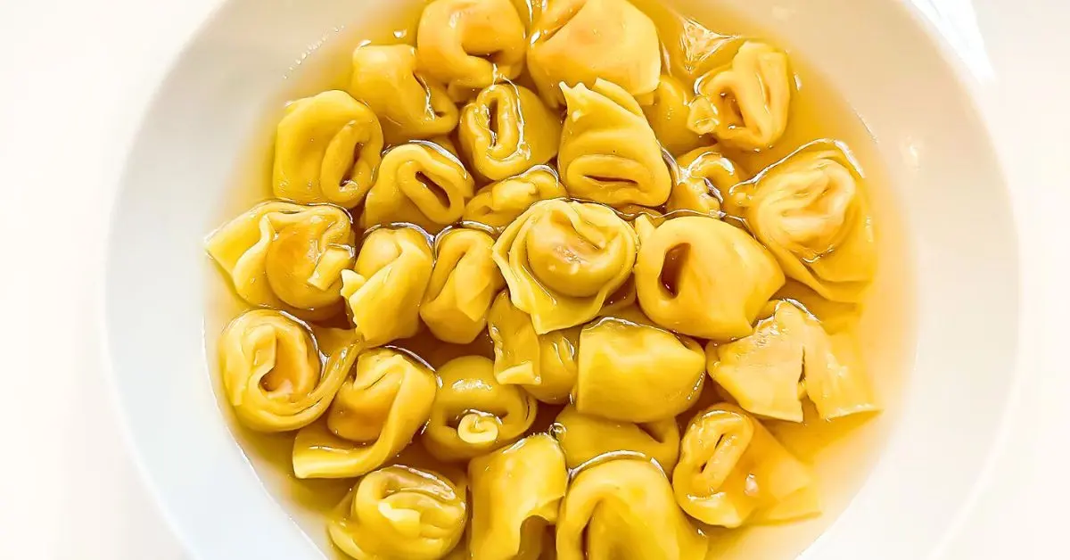 A close-up of tortellini en brodo, a classic dish from the food of Emilia-Romagna, Italy. The golden tortellini pasta floats in a clear, flavorful broth, showcasing the region’s rich culinary traditions.