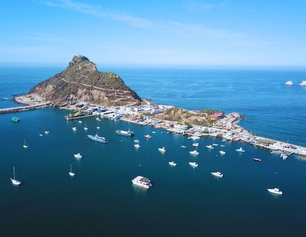 Aerial view of Stone Island Beach and the surrounding harbor from El Faro in Mazatlán, with boats anchored in the water.