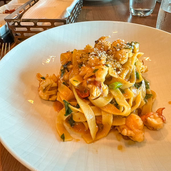 delicious plate of Tagliatelle, from Onda by Scarpetta on the Norwegian Encore. The dish showcases a beautifully prepared pasta with a rich, flavorful sauce, garnished with fresh ingredients.