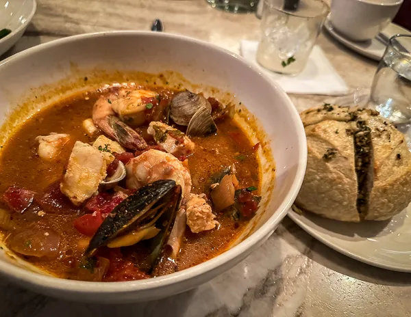 A bowl of Cioppino, a tomato-based seafood stew, served with a side of crusty bread.