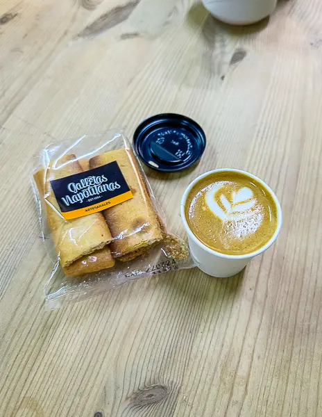 A cafecito and packaged cookies on a wooden table at El Rincon Cafe on Umbrella Street