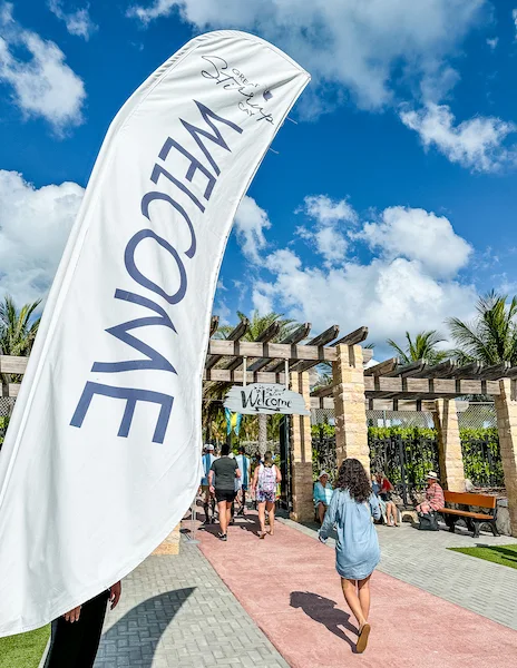 Entrance to Great Stirrup Cay with a large "Welcome" banner with Kathy walking in.