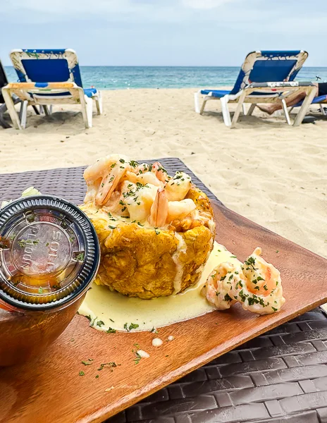 Plate of mofongo with shrimp on a beachside table with the ocean in the background in Puerto Plata