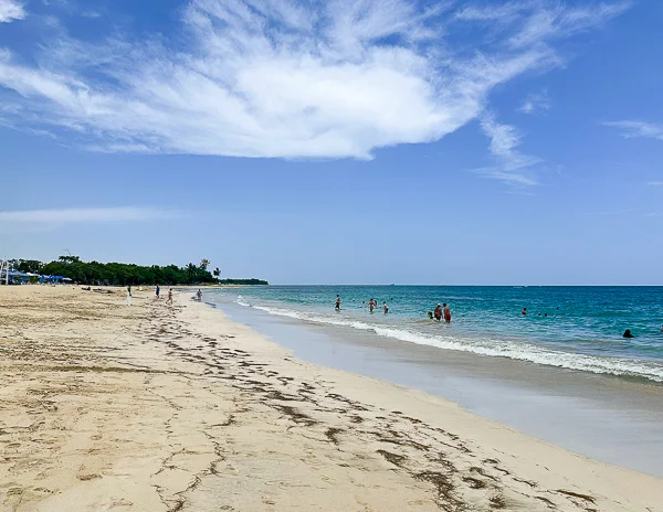 Wide view of the shoreline and ocean at Playa del Pueblito with a few people in the water in Puerto Plata.