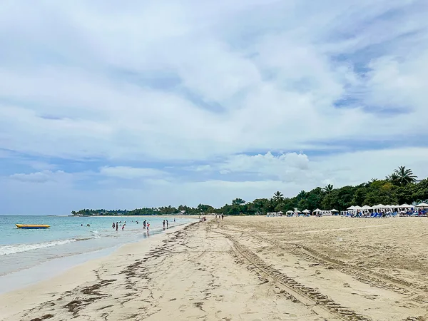 Sandy beach with people swimming and sunbathing at Playa del Pueblito.