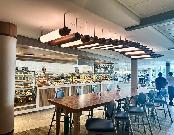 Buffet station inside the Windjammer Café on Utopia of the Seas, featuring a variety of food options, pastries, and seating areas with modern décor.