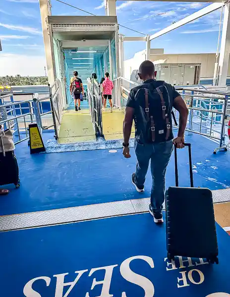 Passenger disembarking from Royal Caribbean's Utopia of the Seas, rolling luggage down the gangway after a cruise experience.