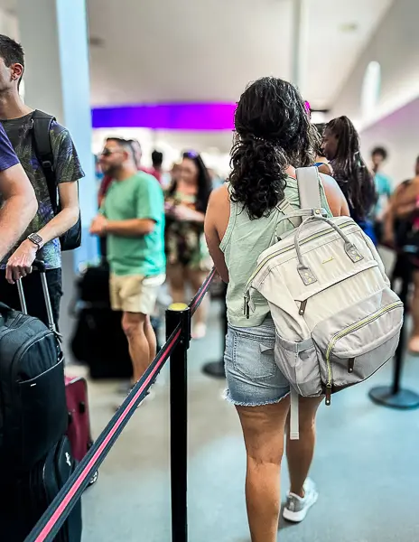 A woman (Kathy) with a backpack waiting in line inside the cruise terminal at Port Canaveral, preparing for security check before boarding Utopia of the Seas.