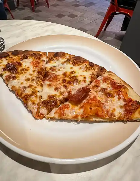 Two slices of cheese and pepperoni pizza from Sorrento’s on Utopia of the Seas, served on a white plate.