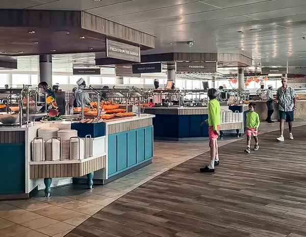 Windjammer Café on Utopia of the Seas, featuring multiple buffet stations with a variety of food options, as passengers browse the selections in a spacious dining area