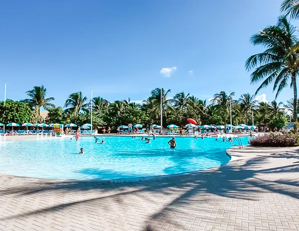 Oasis Lagoon at CocoCay, Royal Caribbean’s private island, showing a large freshwater pool surrounded by loungers and umbrellas under a sunny blue sky.