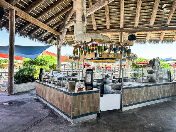 Taco station at Skipper’s Grill in CocoCay, featuring an open-air setup with colorful taco toppings and shaded outdoor seating nearby.