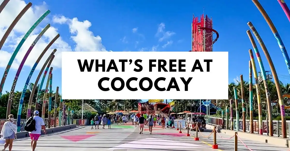 Entrance walkway at CocoCay with colorful archways, people walking, and a tall red water slide in the background, with text overlay reading ‘What’s Free at CocoCay.’