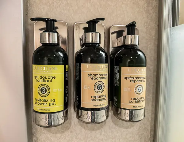 L’Occitane gel, shampoo, and conditioner dispensers mounted in the bathroom of the Haven suite on Norwegian Getaway.