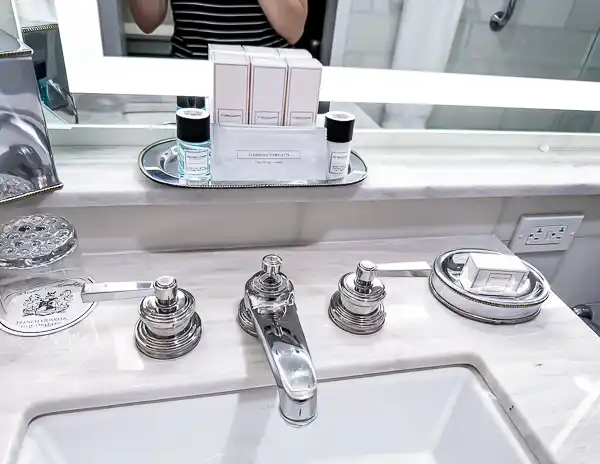 A well-appointed bathroom at Hotel Monteleone, featuring polished chrome fixtures, marble countertops, and a tray of high-end toiletries, providing a luxurious experience.