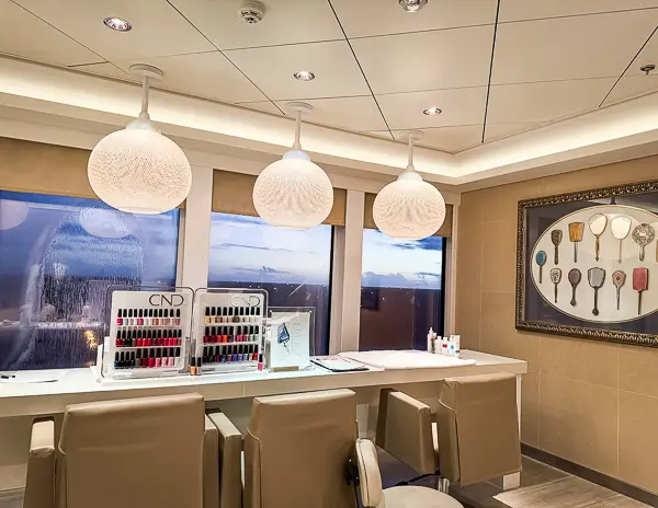 The nail salon at Mandara Spa onboard the Norwegian Getaway, featuring manicure stations with CND nail polish displays, beige chairs, and large windows with ocean views.