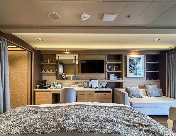 Interior of the Norwegian Getaway Haven Penthouse Suite 14138, featuring a vanity area with a desk, a wall-mounted TV, and cozy seating.