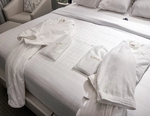 Luxurious white slippers and plush robes laid out on the bed in the King Room at Hotel Monteleone, emphasizing the hotel’s attention to detail and guest comfort.